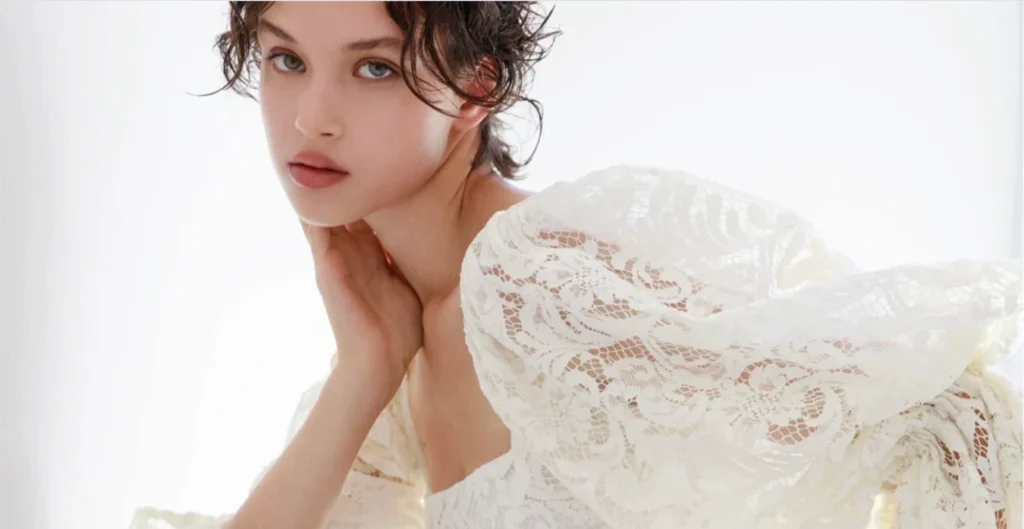 Scatto editoriale realizzato per la campagna Bridal 2026 di Francesca Piccini: protagonista una modella avvolta in un abito in pizzo bianco dalla costruzione romantica e contemporanea, caratterizzato da volumi morbidi, trasparenze delicate e maniche scenografiche che valorizzano la lavorazione sartoriale del capo. La fotografia, immersa in una luce naturale soffusa e minimale, restituisce un’atmosfera intima e senza tempo, mettendo al centro la purezza dei materiali, la ricerca sui dettagli e l’eleganza autentica della maison. Ambientata all’interno della sartoria, cuore creativo del brand, la campagna racconta il valore del fatto a mano e del su misura attraverso un linguaggio visivo raffinato ed essenziale, capace di esprimere una nuova idea di bridal contemporaneo: delicato, consapevole e profondamente identitario. Produzione editoriale e creative direction firmate mm studio per Francesca Piccini | Editorial image created for the Francesca Piccini Bridal 2026 campaign: the photograph features a model wearing a white lace gown with a romantic yet contemporary silhouette, defined by soft volumes, delicate transparencies and dramatic sleeves that highlight the craftsmanship and sartorial construction of the piece. Bathed in soft natural light and framed within a minimal setting, the image conveys an intimate and timeless atmosphere, emphasizing the purity of materials, attention to detail and authentic elegance of the maison. Set inside the atelier — the creative heart of the brand — the campaign celebrates handmade artistry and bespoke tailoring through a refined and essential visual language, expressing a contemporary bridal vision that feels delicate, conscious and deeply personal. Editorial production and creative direction by mm studio for Francesca Piccini.