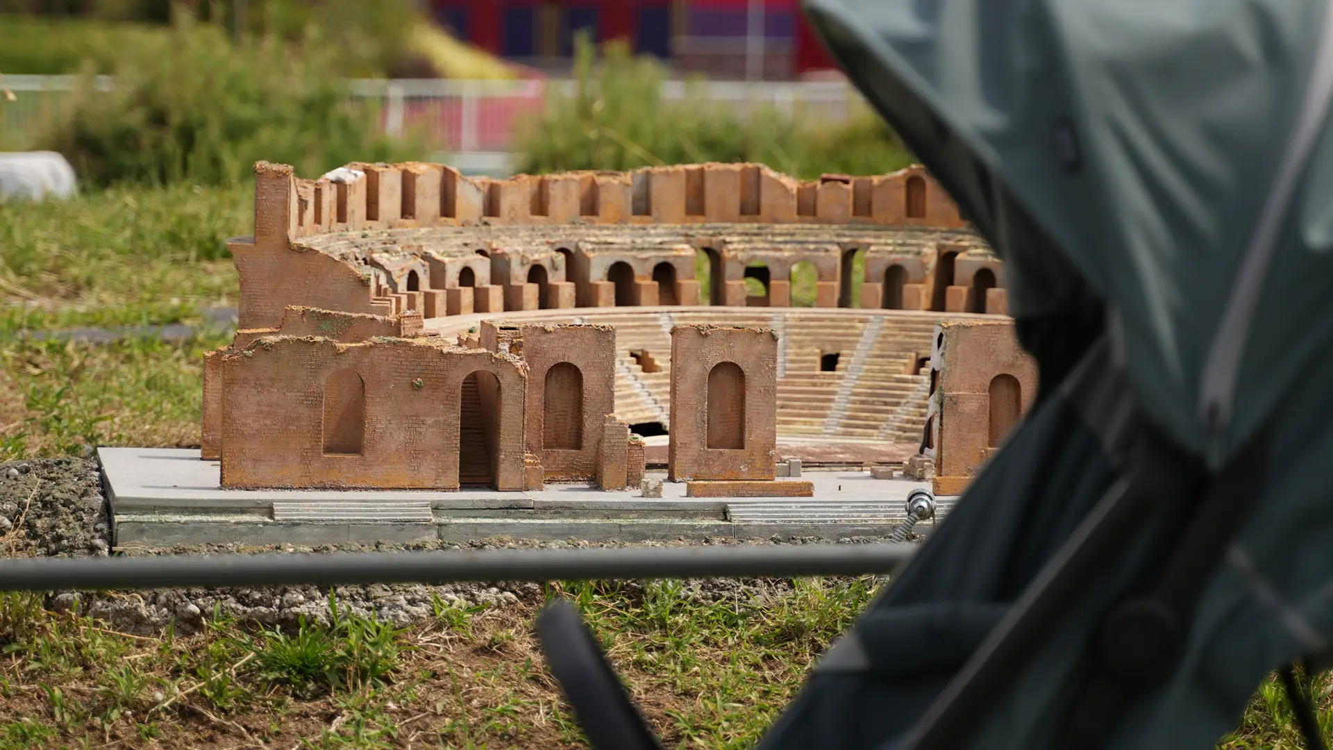 Riproduzione in miniatura di un anfiteatro romano nel parco Leolandia, con la capottina di un passeggino Inglesina sfocata in primo piano / Miniature reproduction of a Roman amphitheatre at Leolandia park, with the hood of an Inglesina stroller blurred in the foreground
